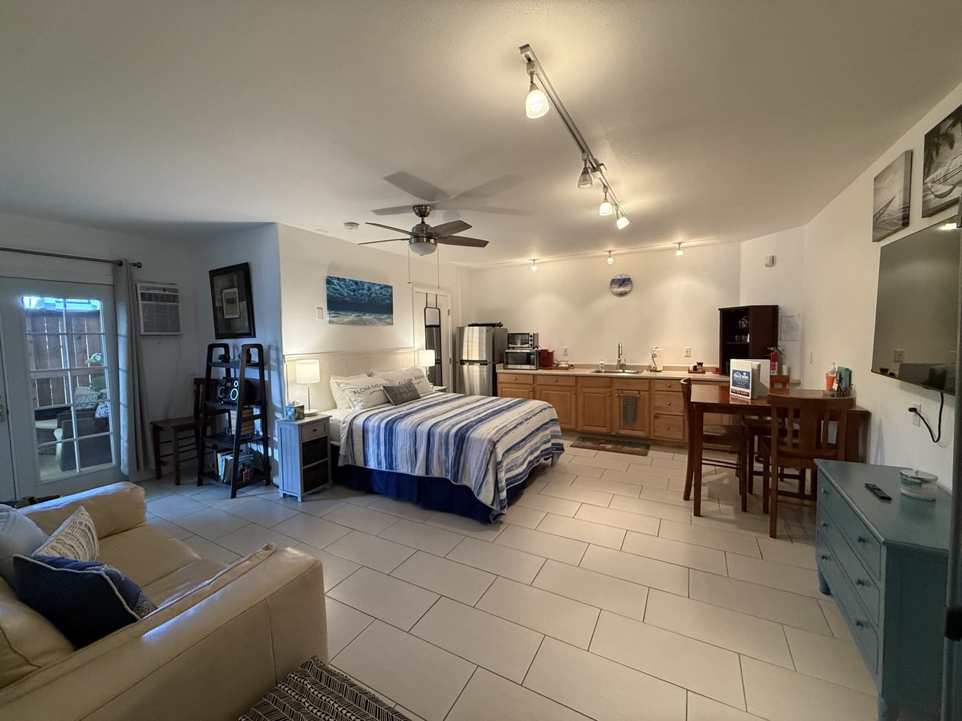 The whole Sunrise studio from the sofa end, with the queen bed on the left and the kitchenette and dining table beyond.