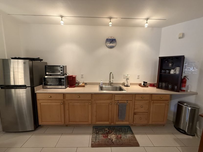 The Sunrise kitchenette head on: full sized refrigerator, toaster oven and microwave, sink, wood cabinets and a wall cabinet.