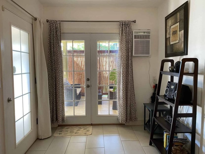 The Sunrise French doors onto the lanai, with the air conditioner and a shelf unit.