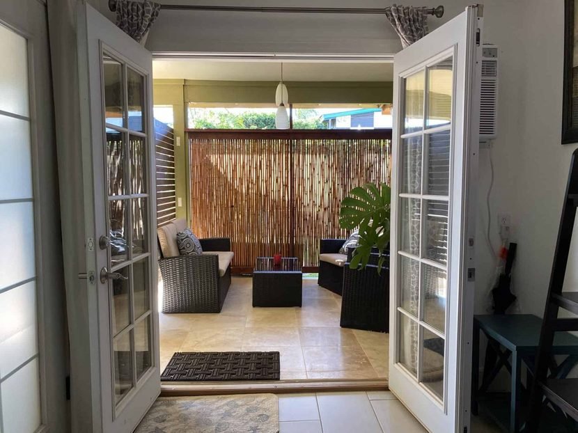 The Sunrise French doors standing open onto the lanai and its wicker seating.