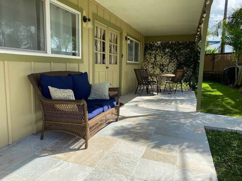 The Sunset lanai with a wicker sofa in blue and a bistro set beyond.