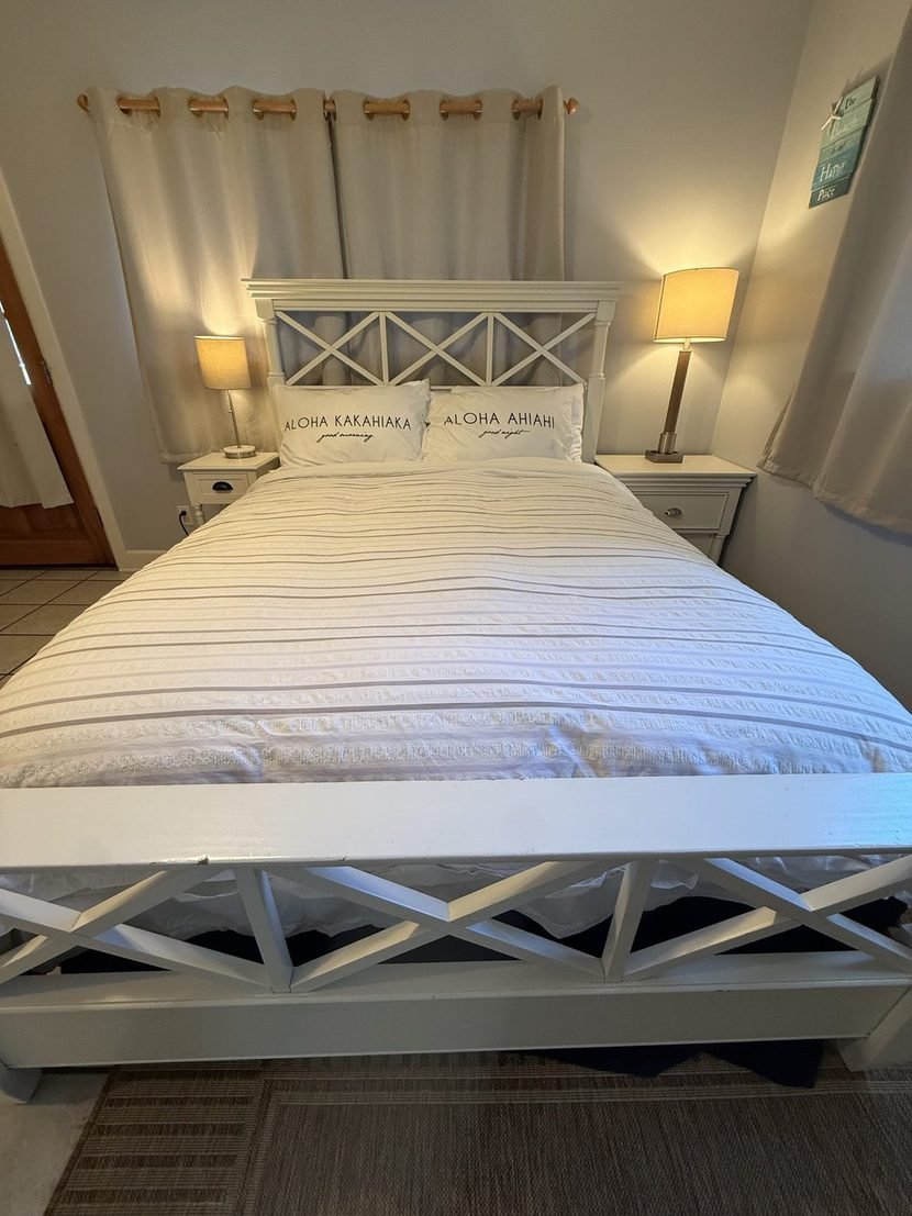The Sunset bed made up in white with Aloha pillows and a lamp on each side.