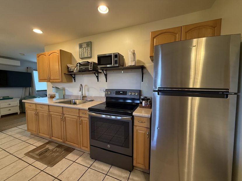 The Sunset kitchen with a full sized refrigerator, an electric range and open shelves.